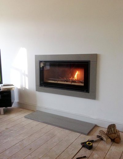 Grey granite contemporary surround and hearth, crafted by Millstone Designs and fitted with a wood burning stove