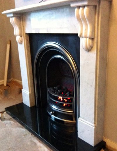 A traditional gas fireplace and surround, fitted with a boxed and lipped granite hearth crafted by Millstone Designs